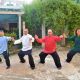 Cuatro personas practicando Tai Chi en un entorno de jardín, combinando a la perfección los movimientos fluidos del Chi Kung, posando en una postura amplia con los brazos extendidos.